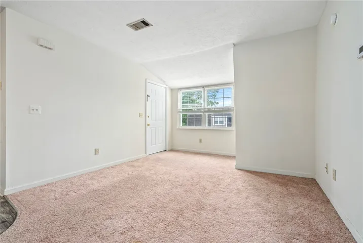 A well-lit room offering plush carpeting and natural light.