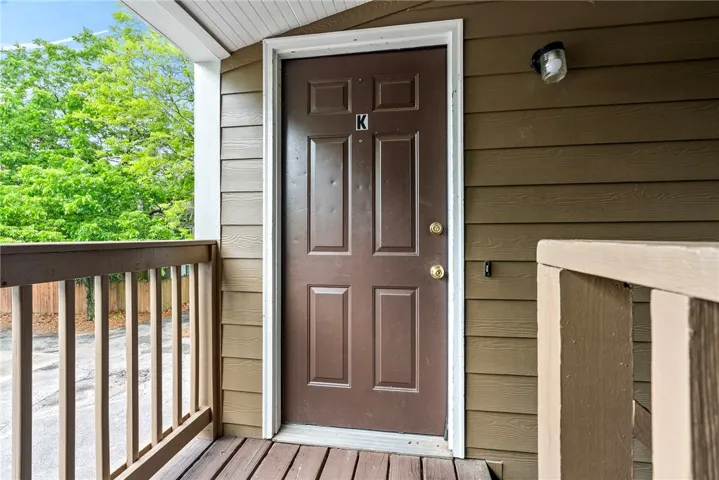 Welcome home to this charming entry with a durable wooden deck and vibrant natural surroundings.
