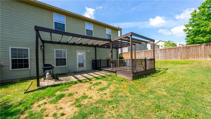 This spacious backyard features a pergola-covered patio and deck, perfect for outdoor living and entertaining.
