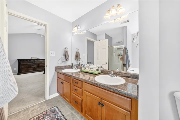 This bathroom features a double vanity and an accessible shower for comfort and convenience.