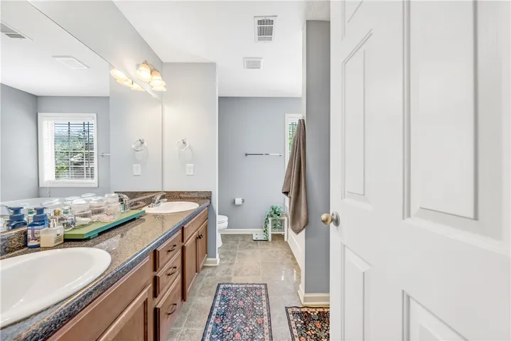 This primary bathroom features double vanities and a large mirror, creating a functional space.