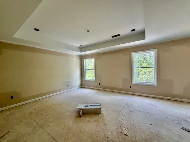 This spacious primary bedroom offers ample natural light and a beautiful tray ceiling.