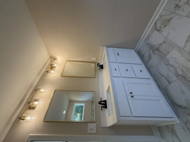 Double vanity with sleek fixtures complements the pristine tiled shower.