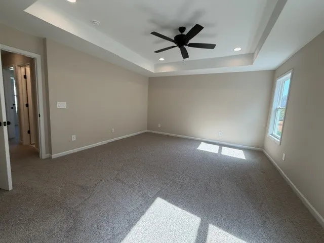 A spacious sleeping quarter features a tray ceiling with a fan and plush carpeting.
