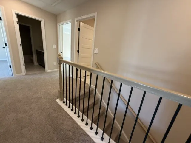 A view from the landing, revealing a carpeted floor, elegant banister, and doorways leading to other rooms.