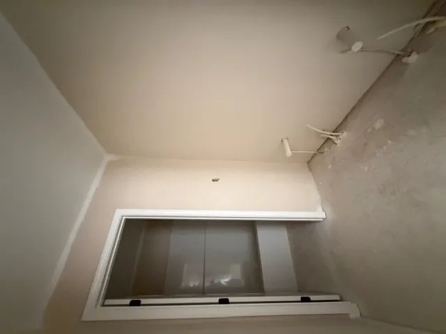 An attic space featuring a window and exposed wiring.