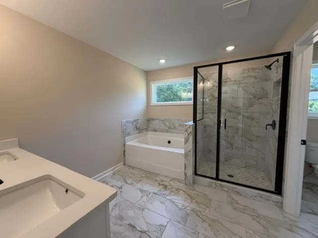 Marble-look tile flooring flows through this bright, well-appointed primary bathroom.