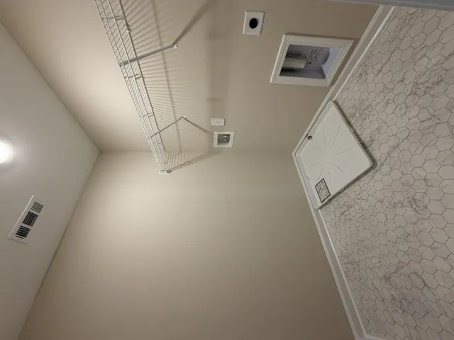 A utilitarian laundry space features a textured tile floor and convenient wire shelving for storage.