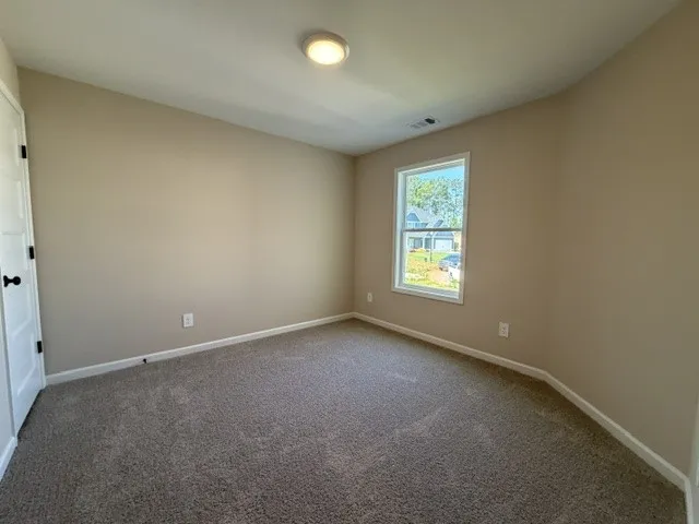 Well-lit room with ample natural light and plush carpeting.