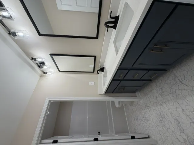 Dual vanity with dark cabinetry and sleek black fixtures provides ample storage in this well-appointed bathroom.