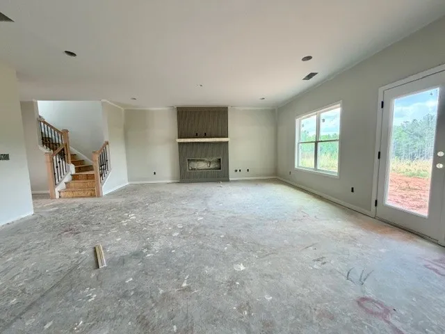 This expansive great room features a prominent fireplace and convenient outdoor access, ideal for gathering.