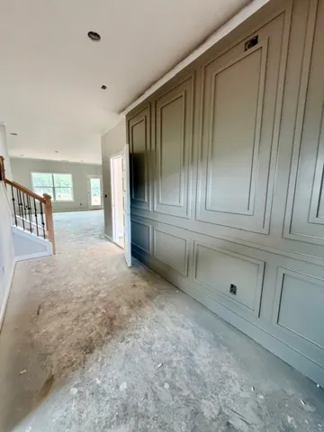 This inviting hallway features wainscoting and leads into a spacious room with ample natural light.