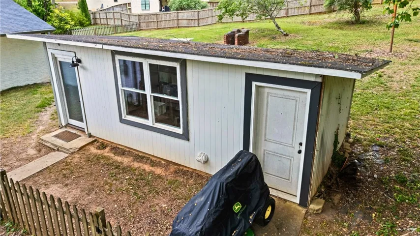 This outdoor storage unit offers versatile utility and garden access with a sturdy fence.