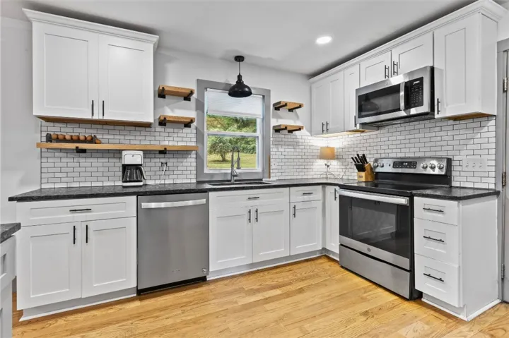 This modern kitchen features crisp cabinetry, sleek countertops, and rich wood flooring.