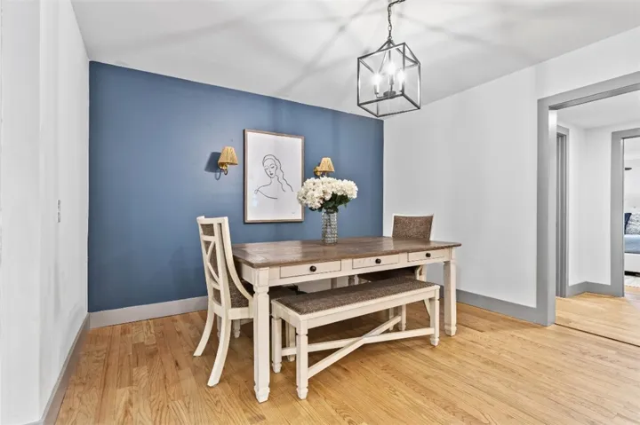 This inviting dining area features warm hardwood flooring and a stylish ceiling light fixture.