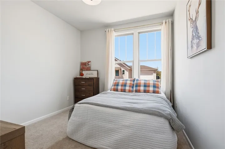 This cozy bedroom features soft carpet and a large window, creating a serene and inviting atmosphere.