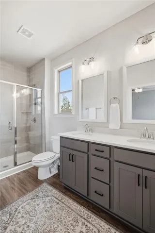 This modern bathroom features a double vanity and a glass-enclosed shower.