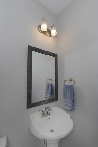 This bathroom features a contemporary pedestal sink and a sleek framed mirror.
