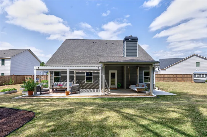 This residence features a charming patio and a lush green yard, perfect for outdoor living.