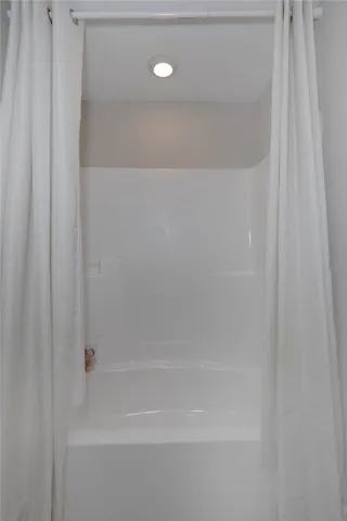 This bright bathroom features a convenient shower-tub combination, ready for everyday use.