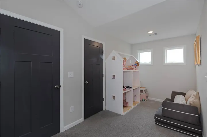 This cozy bedroom features bright windows, soft carpeting, and charming doors, creating a welcoming atmosphere.