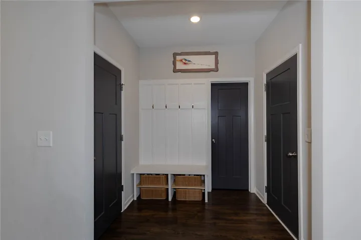 This entry hall features rich wood flooring, leading to a functional built-in storage area.