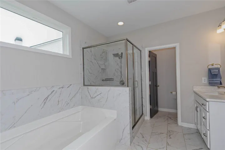 This spacious bathroom offers a serene retreat with a generous soaking tub and a sleek glass-enclosed shower.