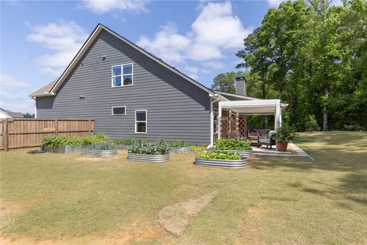 Enjoy outdoor living with a spacious yard featuring a covered patio and garden beds.