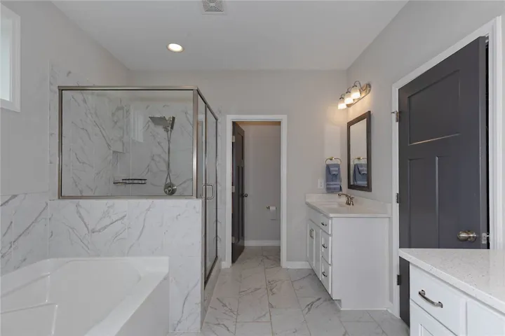 This spacious bathroom offers a relaxing soaking tub and elegant walk-in shower.