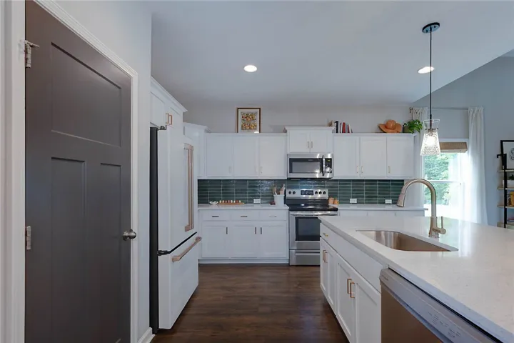 This modern kitchen features bright cabinetry, sleek appliances, and an expansive island with a sink.