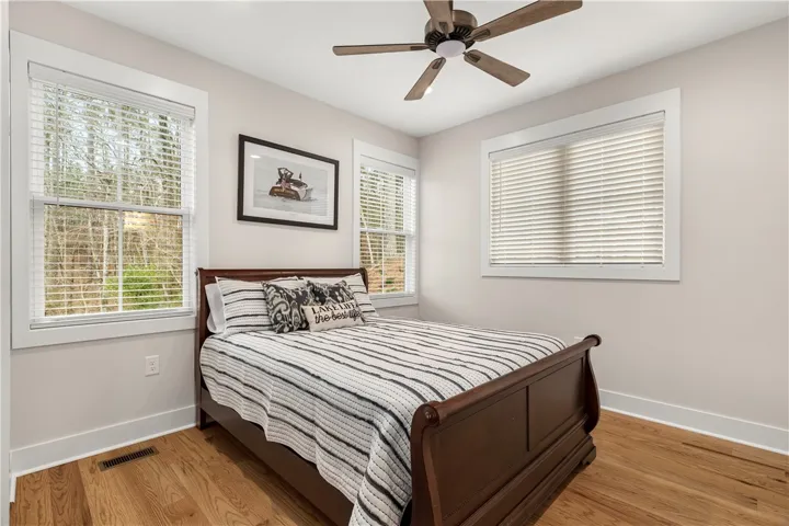This cozy bedroom features warm hardwood floors and abundant natural light through multiple windows.