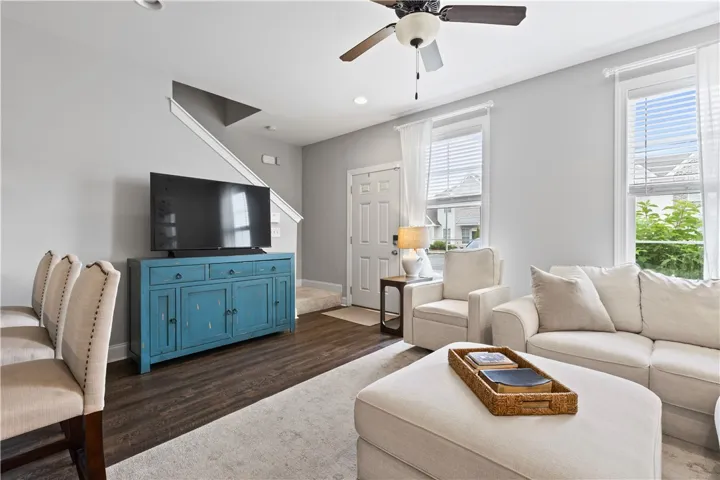 This inviting living space features warm flooring, abundant natural light, and a stylish ceiling fan.