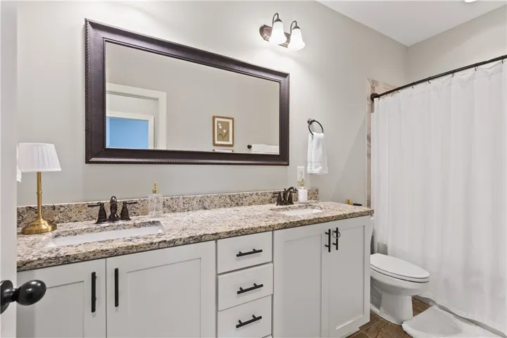 This bathroom features a double vanity with granite counters and a large mirror.