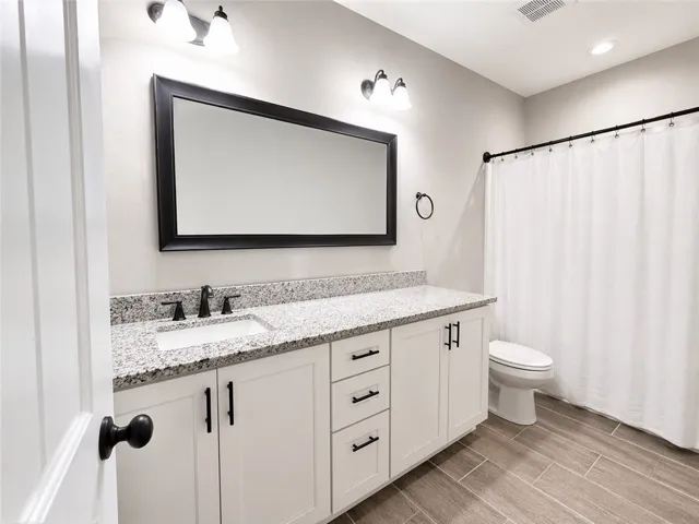 This bathroom features a contemporary vanity and shower, creating a fresh and inviting space.