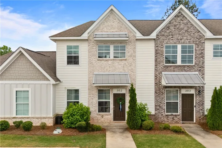 This townhome features a charming exterior with a blend of brick, siding, and gabled rooflines.