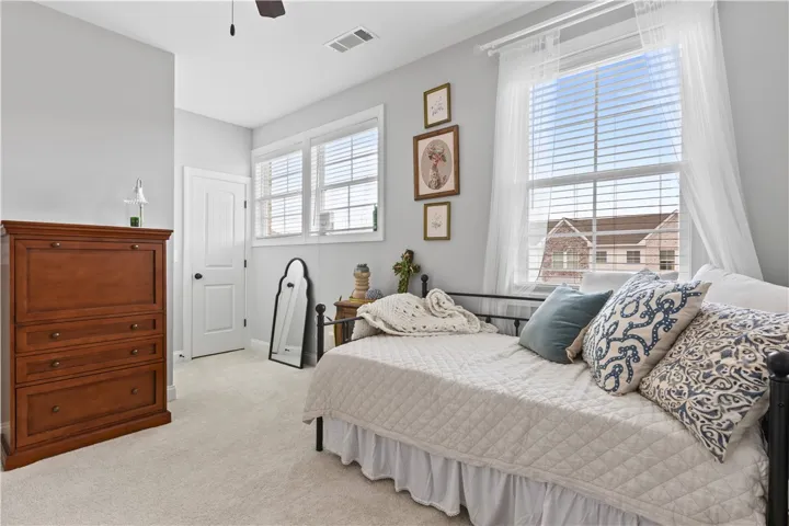 Bright and airy, this comfortable bedroom features soft carpeting and ample natural light.
