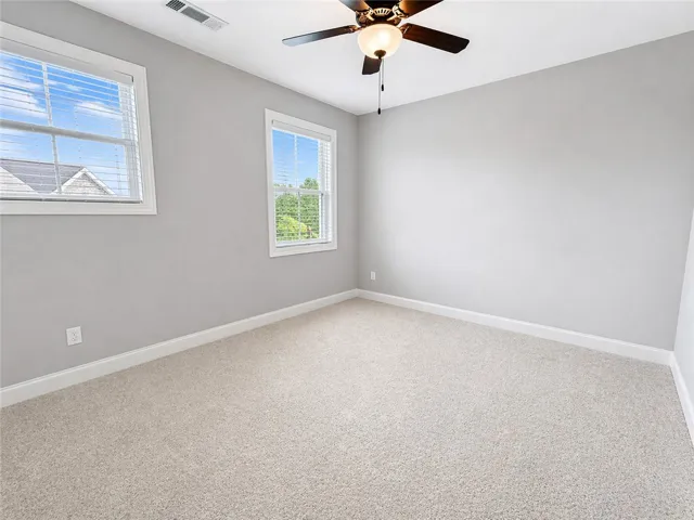 This airy room offers comfort and versatility, featuring ample light from two large windows.