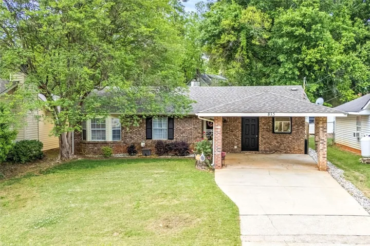 This charming brick home features a brick facade, an inviting covered carport and a beautiful front yard.