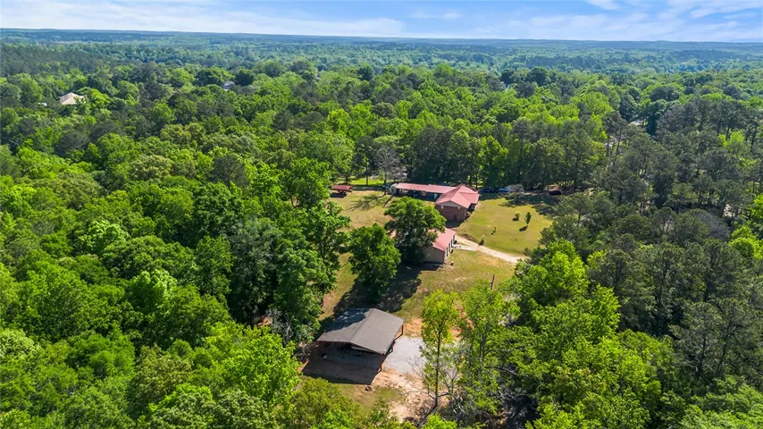 An expansive aerial view showcases a property nestled within a lush, verdant landscape.