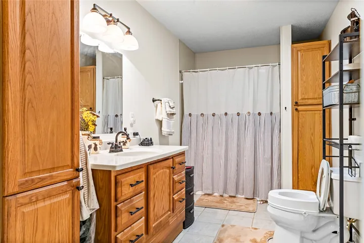 This bathroom features a single vanity, a combination shower and tub, and tile flooring.