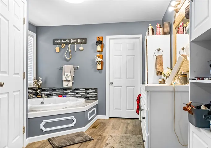 Relax and rejuvenate in this inviting bathroom featuring a soaking tub and elegant wood flooring.