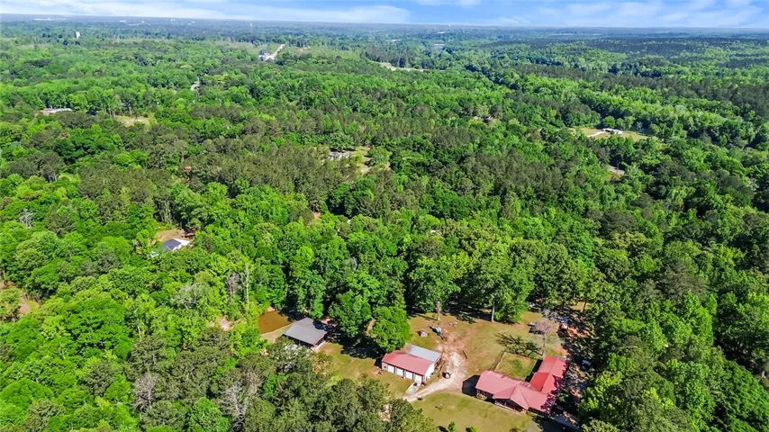 An aerial view captures a property nestled amidst a vast expanse of lush, verdant trees.