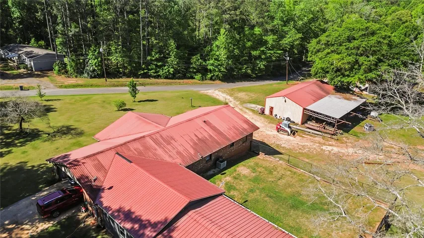 An aerial view showcases a residential property with a main house and an expansive metal-roofed barn.