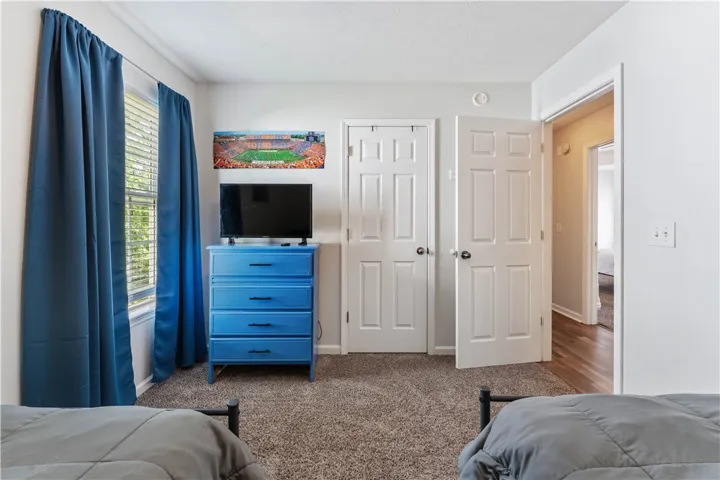 This cozy bedroom features durable carpet flooring and bright natural light from a window with blinds.