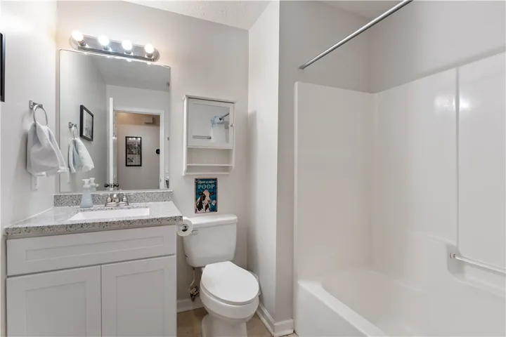This bright bathroom features granite counters and a clean, functional tub.