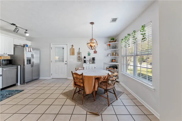 This bright eat-in kitchen features a unique spherical chandelier, white cabinetry, and durable tile flooring.
