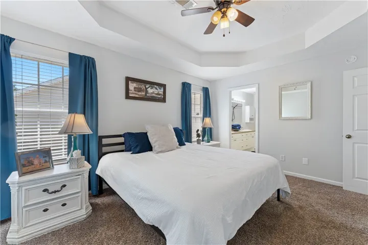 This spacious bedroom offers ample comfort, featuring soft carpeting and a private entrance to the bathroom.
