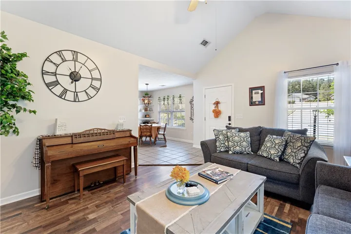 This inviting living space features warm flooring and a view into the dining area.