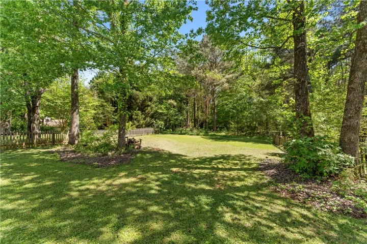 This expansive, verdant yard offers a tranquil retreat surrounded by mature trees.