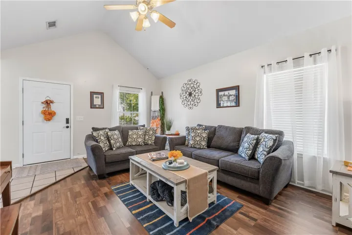 This inviting living space features warm flooring, abundant natural light, and vaulted ceilings.